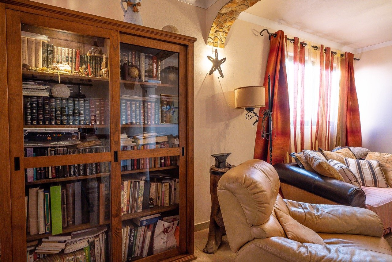 A cozy whitewashed living room with linen sofa, ceramic vase, and warm afternoon light